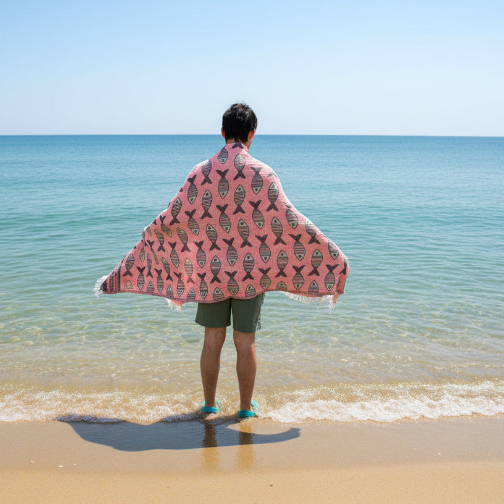 Person holding a pink towel with fish pattern on grass